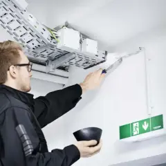 Mann dichtet Kabeldurchführung ab. Wichtig für Brandschutz Firmen, um Sicherheit zu gewährleisten.