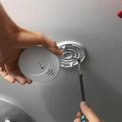 Mann schraubt Rauchmelder an Decke. Einfache Rauchmelder Wandmontage für mehr Sicherheit.