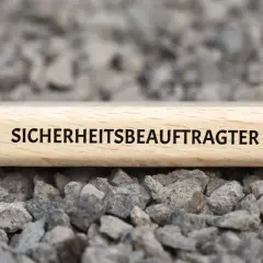 Holzblock mit der Aufschrift "SICHERHEITSBEAUFTRAGTER" auf Schotter. Ab wann ist man Sicherheitsbeauftragter?