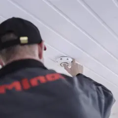 Ein Mann mit Kappe montiert einen kalo rauchmelder an der Decke.