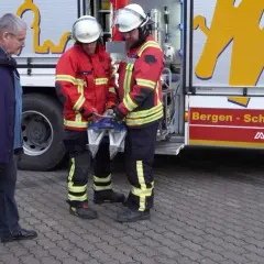 Zwei Feuerwehrmänner mit Rettungsgerät, ein Mann in Zivil. Frage: ab wann darf man bei der freiwilligen feuerwehr einsätze mitfahren?