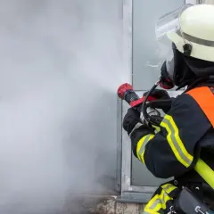 Feuerwehrmann im Einsatz mit Sprühstrahl, ein Beispiel für die vielfältigen Berufe bei der Feuerwehr.