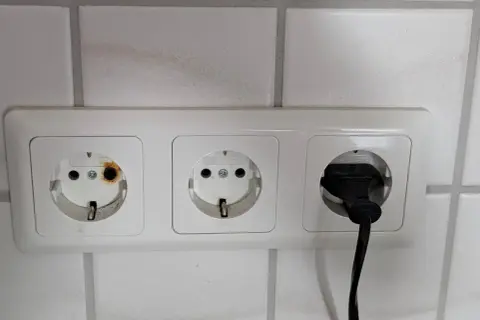 Eine Steckdose ist durchgebrannt, mit deutlichen Brandspuren im linken Anschluss. Ein Stecker ist im rechten Anschluss.