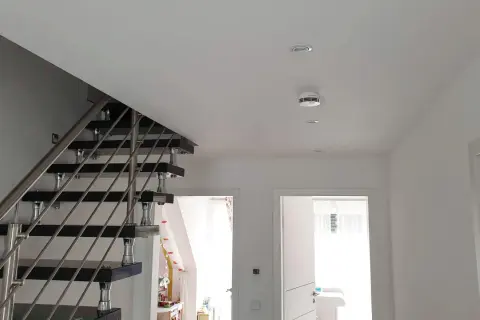 Moderner Flur mit Treppe und einem weißen rauchmelder an der Decke, der für Sicherheit sorgt.