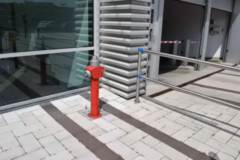 Ein roter hydrant steht auf einem gepflasterten Weg. Er ist bereit, im Notfall eine hohe hydrant durchflussmenge zu liefern.