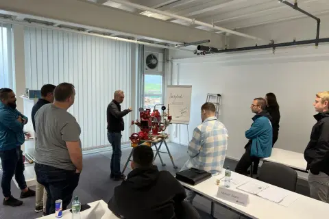 Männer nehmen an einer Schulung teil, bei der ein Sprinklerwart die Funktionsweise eines Sprinklersystems erklärt.