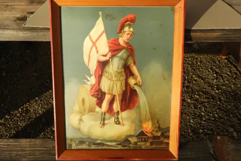 Gemälde zeigt den Heiligen Florian, der mit einem Krug Wasser ein brennendes Dorf löscht.