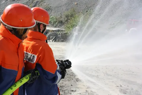 Zwei Feuerwehrleute üben mit einem Schlauch, wie im Feuerwehrgesetz Niedersachsen vorgeschrieben.