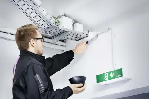 Mann dichtet Kabeldurchführung ab. Wichtig für Brandschutz Firmen, um Sicherheit zu gewährleisten.