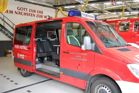 Rotes Feuerwehrauto mit Blaulicht, bereit für Einsätze und Veranstaltungen. Aufschrift "FEUERWEHR" und "FEUER/NOTFALL".