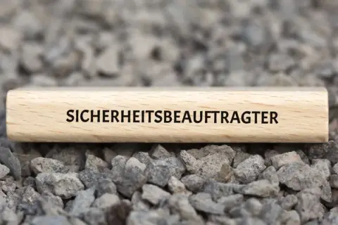 Holzblock mit der Aufschrift "SICHERHEITSBEAUFTRAGTER" auf Schotter. Ab wann ist man Sicherheitsbeauftragter?