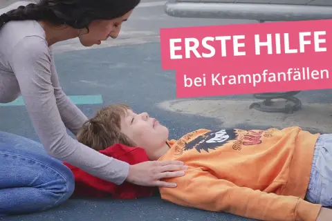 Erste Hilfe bei Krampfanfällen: Eine Frau kniet neben einem Kind, das auf dem Boden liegt.