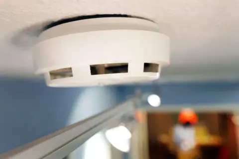 Ein weißer Rauchmelder an der Decke, wichtig für Mieter und Vermieter zur Sicherheit.