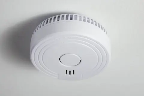 Ein weißer Funkrauchmelder an der Decke. Mögliche Nachteile von Funkrauchmeldern sind die Abhängigkeit von Batterien und Funkstörungen.