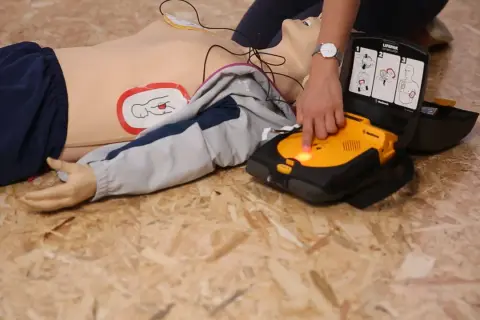 Schulung: Ein Defibrillator wird an einer Übungspuppe angewendet. Die Defibrillator-Pflicht ist wichtig für Erste Hilfe.