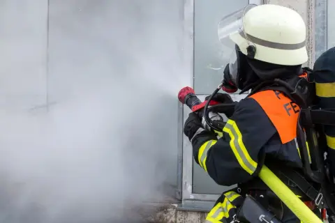 Feuerwehrmann im Einsatz mit Sprühstrahl, ein Beispiel für die vielfältigen Berufe bei der Feuerwehr.