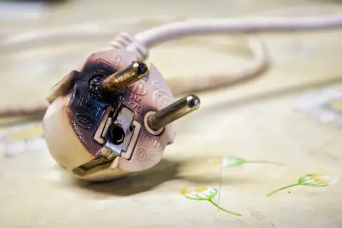 Beschädigter Stecker zeigt, wie entsteht ein Kabelbrand durch Überlastung oder Defekt. Vorsicht ist geboten!
