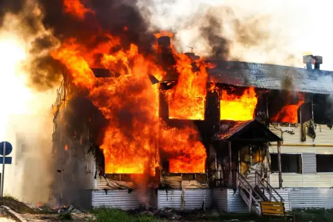 Ein Haus brennt lichterloh. Die Flammen schlagen aus den Fenstern. Hoffnung auf finanzielle Hilfe nach Brand ohne Versicherung.