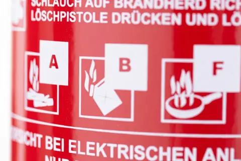 Symbole für Brandklasse A, B und F auf rotem Feuerlöscher. Wichtige Hinweise zur Brandbekämpfung.