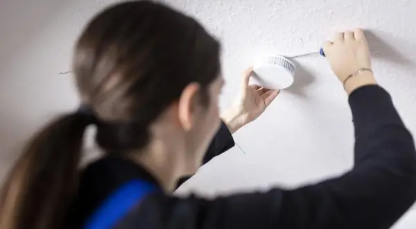 Frau tauscht Rauchmelder aus, da die Frist abgelaufen ist. Sicherheit geht vor!