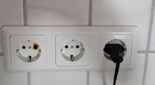 Eine Steckdose ist durchgebrannt, mit deutlichen Brandspuren im linken Anschluss. Ein Stecker ist im rechten Anschluss.