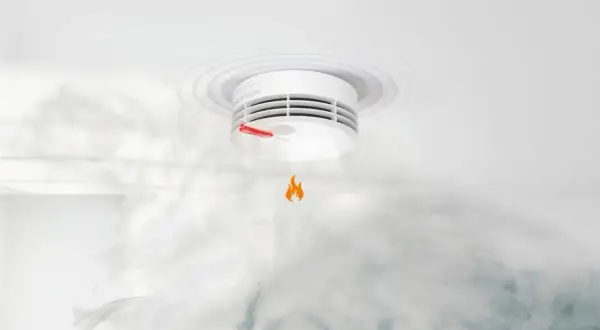 Ein **Genius Plus Rauchmelder piept** und warnt vor Rauch und einer kleinen Flamme.