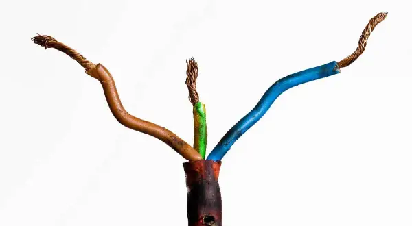 Beschädigte Kabel mit freiliegenden Drähten, die auf einen möglichen kabelbrand geruch hindeuten. Die Isolierung ist an einer Stelle geschmolzen.