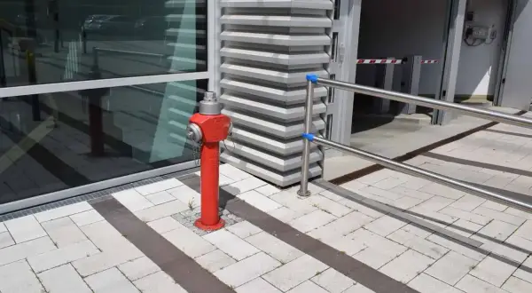 Ein roter hydrant steht auf einem gepflasterten Weg. Er ist bereit, im Notfall eine hohe hydrant durchflussmenge zu liefern.