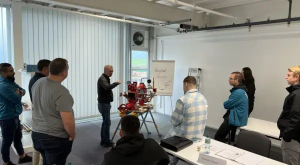 Männer nehmen an einer Schulung teil, bei der ein Sprinklerwart die Funktionsweise eines Sprinklersystems erklärt.