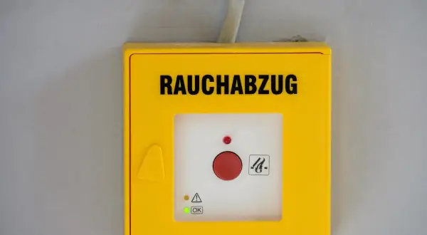 Gelbes Gehäuse für Rauchabzug mit rotem Knopf. Ein grünes Licht zeigt "OK" an, was auf ein erfolgreiches Wartungsprotokoll RWA Muster hindeutet.