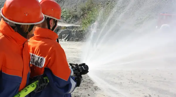 Zwei Feuerwehrleute üben mit einem Schlauch, wie im Feuerwehrgesetz Niedersachsen vorgeschrieben.