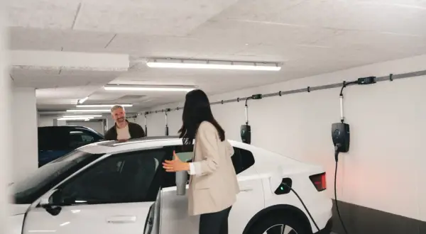 Frau und Mann in Tiefgarage bei Wallbox-Ladestation. Brandschutz ist hier wichtig, während das Elektroauto geladen wird.