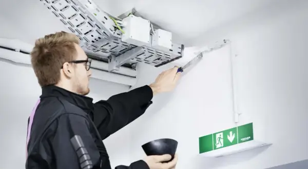 Mann dichtet Kabeldurchführung ab. Wichtig für Brandschutz Firmen, um Sicherheit zu gewährleisten.