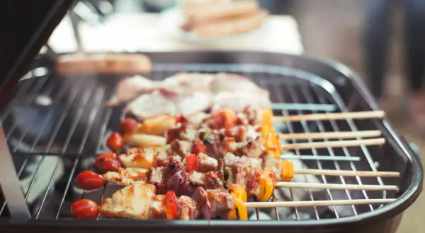 Fleischspieße mit Gemüse brutzeln auf einem Grill. Ein gemütliches Grillen in der Wohnung, auch bei schlechtem Wetter.