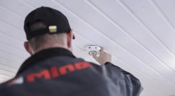 Ein Mann mit Kappe montiert einen kalo rauchmelder an der Decke.