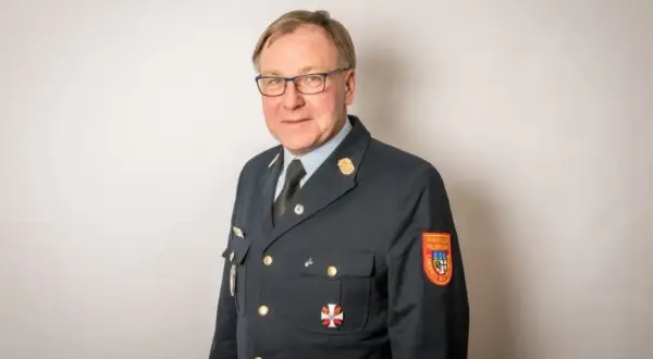 Mann in Uniform mit Orden und Aufnäher "Freiwillige Feuerwehr". Sein Kreisbrandrat Gehalt ist wohl angemessen für diese Verantwortung.