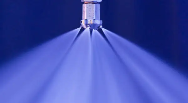 Ein Sprühkopf zerstäubt blaues Wasser. Was bedeutet VDS? Vielleicht die Abkürzung für "Verdampfung durch Sprühen".