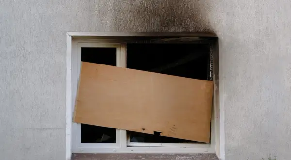 Beschädigtes Fenster, provisorisch mit Holzplatte verschlossen. Die Frage, wie lange bleibt eine Wohnung versiegelt, bleibt offen.