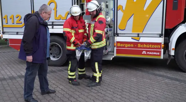 Zwei Feuerwehrmänner mit Rettungsgerät, ein Mann in Zivil. Frage: ab wann darf man bei der freiwilligen feuerwehr einsätze mitfahren?