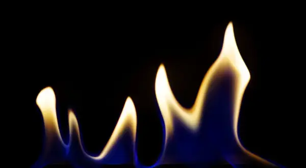 Blau-gelbe Flammen tanzen im Dunkeln, eine Warnung vor den ethanol gefahren.