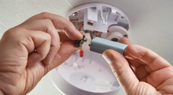 Hände wechseln Batterie eines Rauchmelders. Wichtig für die Versicherung und Sicherheit.