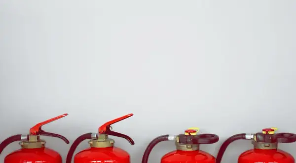 Vier rote Feuerlöscher stehen nebeneinander. Sie enthalten ABC-Pulver, das bei Bränden nützlich ist, aber nicht giftig ist.