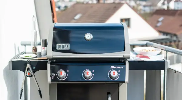 Weber Gasgrill auf dem Balkon: Grillen erlaubt! Mit Fleisch und Gewürzen bereit für den Genuss.