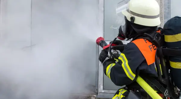 Feuerwehrmann im Einsatz mit Sprühstrahl, ein Beispiel für die vielfältigen Berufe bei der Feuerwehr.