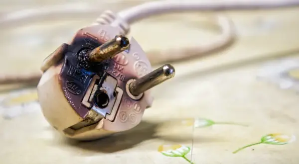 Beschädigter Stecker zeigt, wie entsteht ein Kabelbrand durch Überlastung oder Defekt. Vorsicht ist geboten!