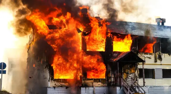 Ein Haus brennt lichterloh. Die Flammen schlagen aus den Fenstern. Hoffnung auf finanzielle Hilfe nach Brand ohne Versicherung.