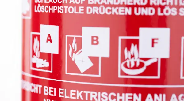 Symbole für Brandklasse A, B und F auf rotem Feuerlöscher. Wichtige Hinweise zur Brandbekämpfung.