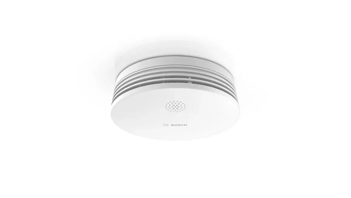 Ein weißer Rauchmelder von Bosch, der an der Decke montiert ist. Er zeigt das Bosch-Logo und eine Lautsprecheröffnung. Hier erfahren Sie, wie Sie die Bosch TwinGuard Batterie wechseln.