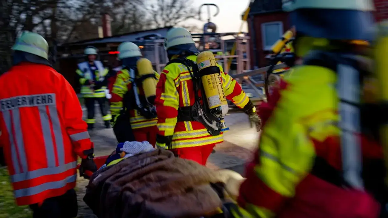 Feuerwehrleute im Einsatz nach einem Brand in einem alten Heim. Sie tragen Schutzkleidung und Atemschutzgeräte.