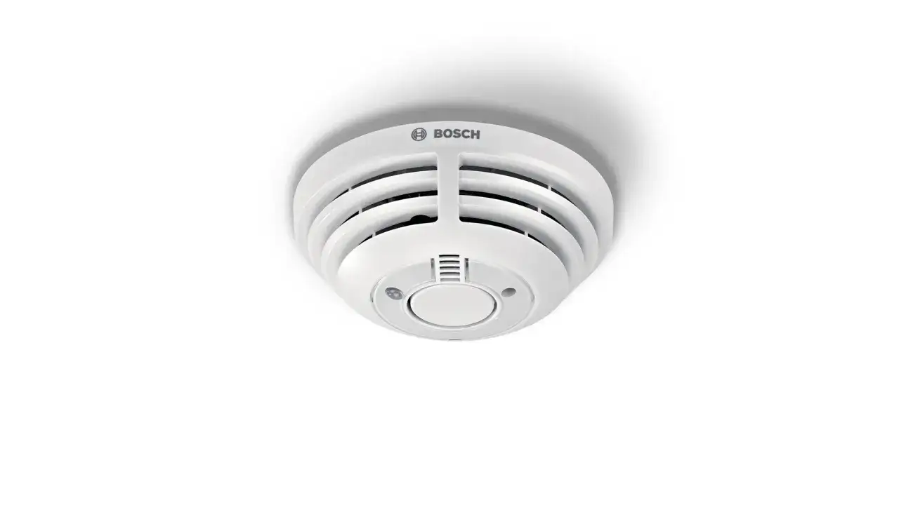 Ein wei&szlig;er Bosch Smart Home Rauchmelder mit rotem Blinklicht, der auf einer Decke montiert ist.